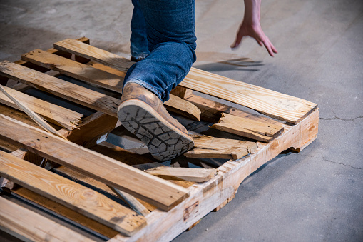 Male worker falls through a wooden pallet while on the job.