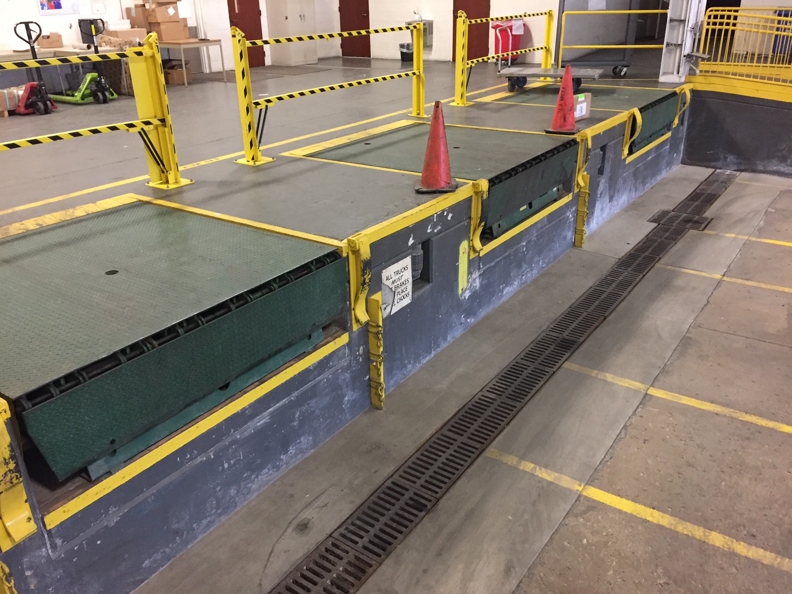 A loading dock with orange safety cones and yellow barriers.
